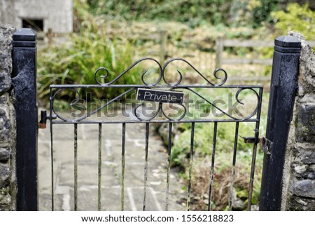 Private sign on black wrought iron gate to garden rustic stone