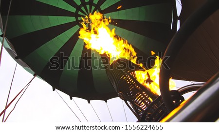Adventure on hot air balloon watermelon. Burner directing flame into envelope. The aircraft fly in morning blue sky due to hot air. Hot air burning gas fire to air balloon or aerostat during flight.