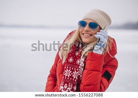 Blonde woman in red jacket outside in winter talking on the phone