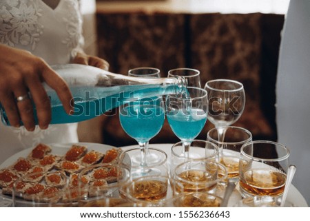 snack table, sandwiches with red caviar, blue sparkling wine, whiskey with ice, selective focus, film and grain photo