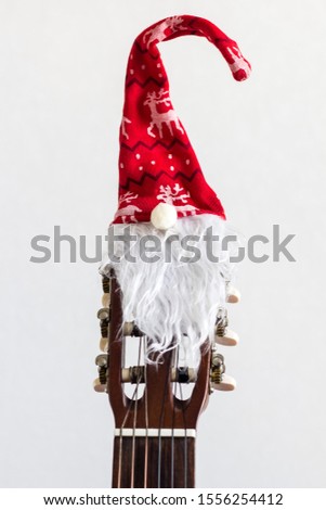 acoustic guitar with red Santa hat. Christmas song music concept on white background with copyspace