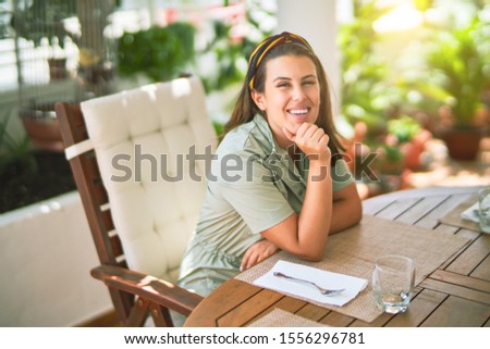 Young beautiful woman sitting on terrace smiling