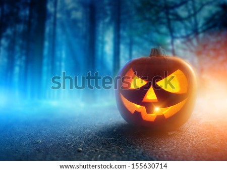 A glowing Jack O Lantern in a dark mist Forest on Halloween...