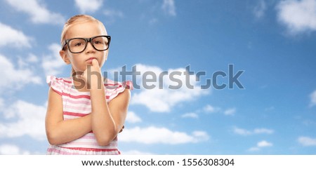 education, school and vision concept - cute little girl in black glasses over blue sky and clouds background