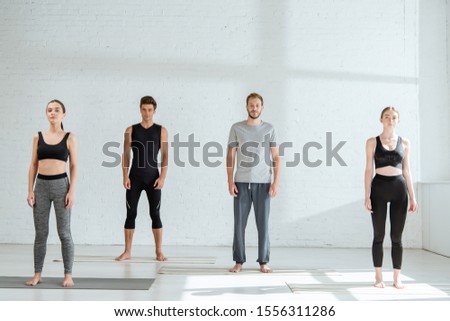 young people in sportswear standing in mountain pose