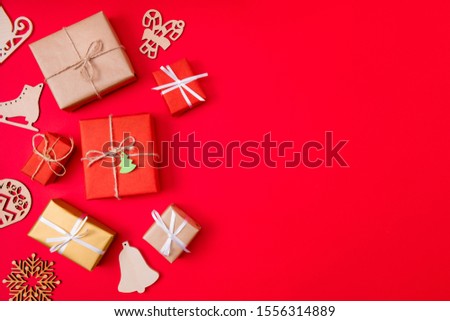 Photo of creative conept of presents wrapped among new year items like bells skates and snowflakes near copyspace isolated vibrant color red background