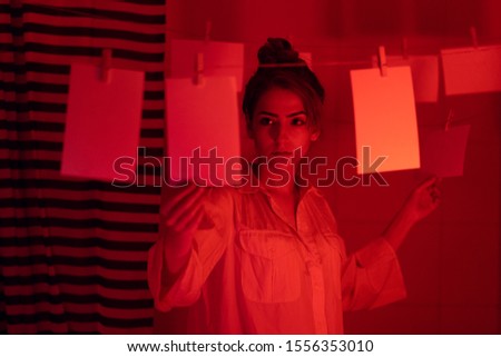 hobbyist or professional photographer. Young girl developing photos in a dark room. Retro style photography