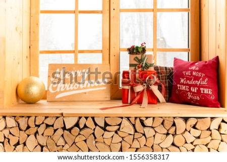 Cozy and frost winter day: christmas decoration on wood windowsill and snow landscape from outside.