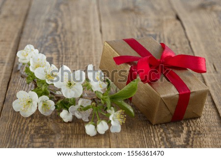 Gift box with branch of beautiful jasmine flowers on the wooden background. Concept of giving a gift on holidays.