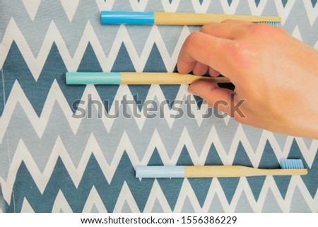 Wooden toothbrush on blue background. Hand touch 