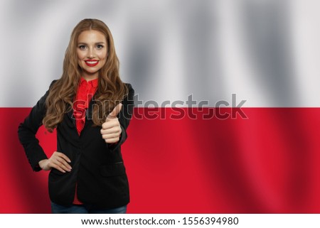 Cute young woman showing thumb up on the Poland flag background. Travel and learn polish language concept Royalty-Free Stock Photo #1556394980