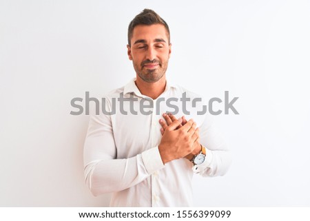 Young handsome business man wearing elegant shirt over isolated background smiling with hands on chest with closed eyes and grateful gesture on face. Health concept.