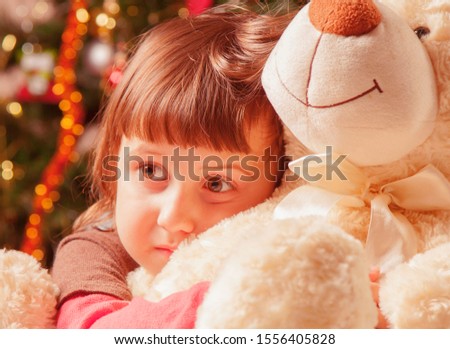 Christmas picture of little beautiful girl hugging teddy bear at home and waiting for Christmas and Santa Claus.