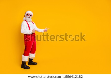 2020 christmas time! Funny funky grandfather in red santa claus hat point index finger copyspace indicate noel tradition x-mas discount wear  isolated over yellow color background