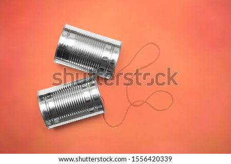 Communications and business calls concept of tin can telephone with string on orange Royalty-Free Stock Photo #1556420339