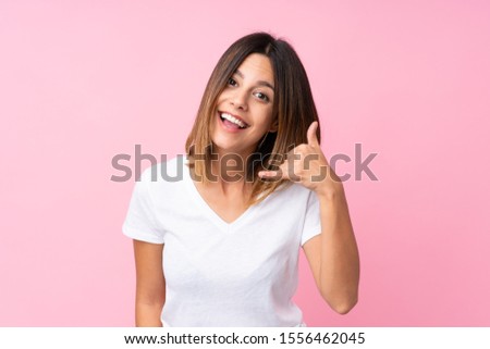 Young woman over isolated pink background making phone gesture. Call me back sign