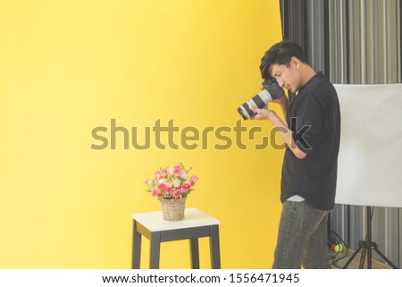 Asian Young male professional photographer shooting photo with a digital camera in a professionally equipped studio.