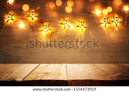 background image of wooden board table in front of Christmas warm gold garland lights. filtered. selective focus. glitter overlay