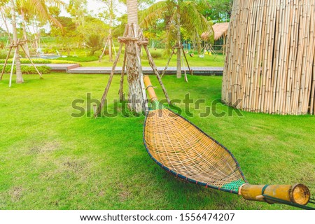 Bamboo wicker hammock hanging on tree for relaxing in the public garden.