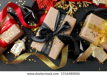 Craft gift boxes with gold  balck ribbon on shine black background. Merry Christmas greeting card, Sale. Winter xmas holiday theme. Happy New Year 2022. Close up