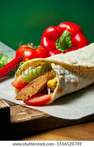 Vegetarian shawarma roll in pita with soy sausage, vegetables, and fried tofu. Tasty, wholesome and green food. Vegan street food