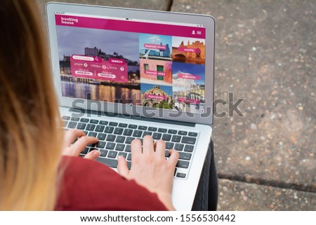 Close up view of woman with laptop booking a hotel on website. Travel concept. All screen graphics are made up by us