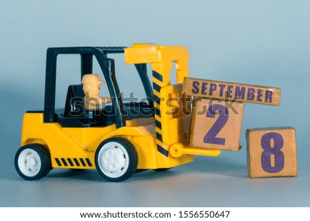 september 28th. Day 28 of month,  Construction or warehouse calendar. Yellow toy forklift load wood cubes with date. Work planning and time management. autumn month, day of the year concept.