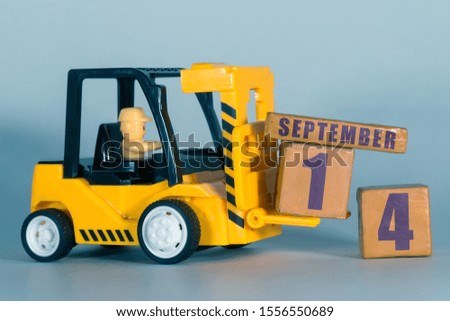 september 14th. Day 14 of month,  Construction or warehouse calendar. Yellow toy forklift load wood cubes with date. Work planning and time management. autumn month, day of the year concept.