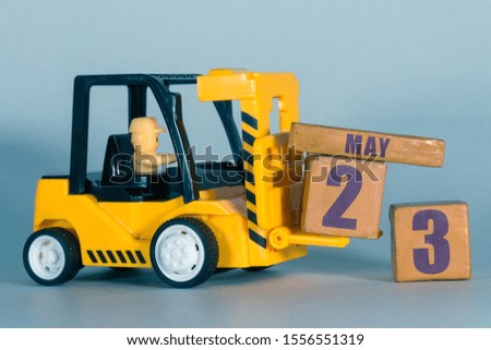 may 23rd. Day 23 of month,  Construction or warehouse calendar. Yellow toy forklift load wood cubes with date. Work planning and time management. spring month, day of the year concept.