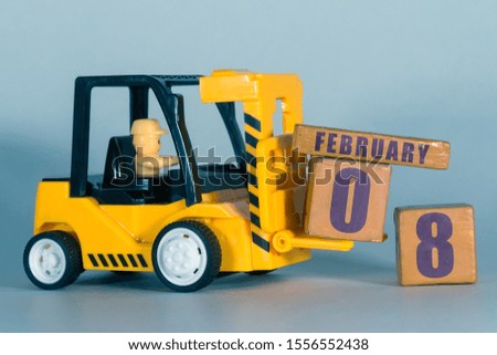 february 8th. Day 8 of month,  Construction or warehouse calendar. Yellow toy forklift load wood cubes with date. Work planning and time management. winter month, day of the year concept.