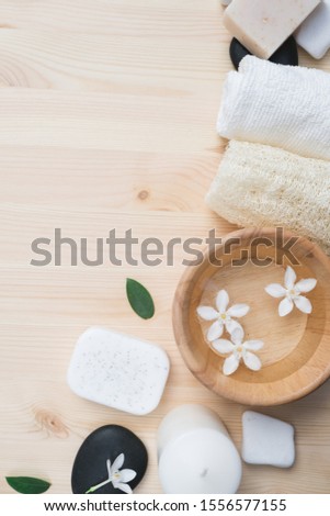 Spa products with sea salt in bowl, towels, scrub, aroma oil in bottles and flowers on vintage wooden background. Flat lay Spa composition with body care items.
