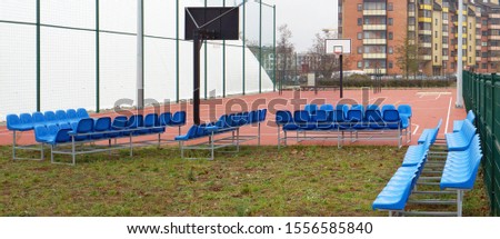 Blue plastic benches on metal frames near the new modern  basketball  stadium in small European city
