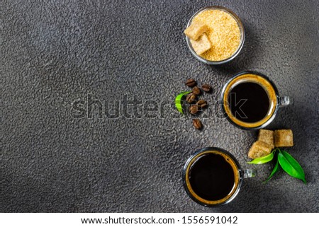 Black coffee with brown sugar on dark background. Top view, copy space.