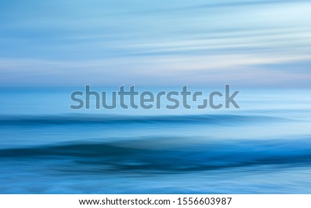 Intentional camera movement creating a dreamy, blurred effect of the sea at Brighton and Hove, East Sussex. Royalty-Free Stock Photo #1556603987