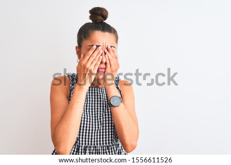 Beautiful woman with bun wearing casual dresss standing over isolated white background rubbing eyes for fatigue and headache, sleepy and tired expression. Vision problem