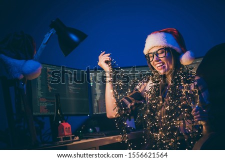 Photo of skilled it specialist business lady with sparkling wine glass at corporate company newyear party say toast laughing best night wear garland lights santa cap glasses office indoors