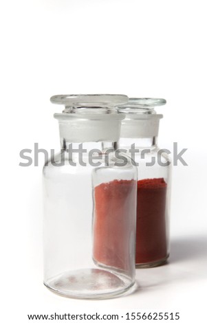 Achiote is a shrub native to a region between northern South America and Mexico. Bixa orellana is grown in many countries worldwide. The seeds are natural orange. Glass bottle over white background.