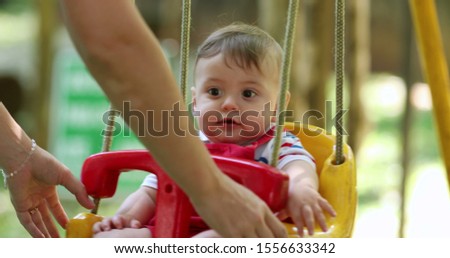 
Cute adorable baby boy at park swing outdoors mom pushing infant son at playground swing