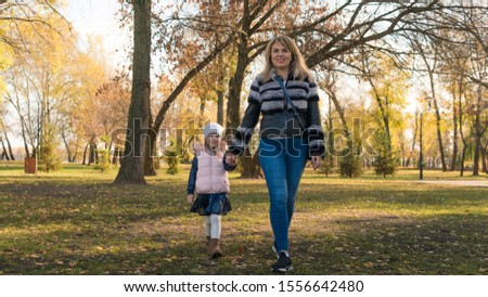 Happy mother and her daughter spending time in the autumn city park. Concept of Mother Day and parent love.