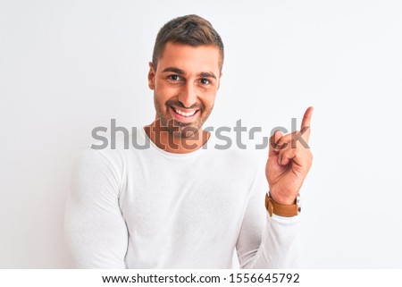 Young handsome man wearing white shirt over isolated background with a big smile on face, pointing with hand and finger to the side looking at the camera.