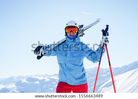 Photo of athlete man in helmet and mask with skis on his shoulder