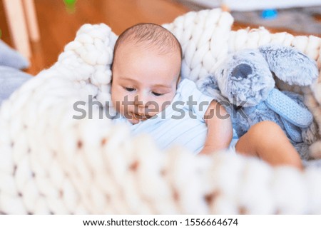 Adorable baby lying down over blanket on the floor at home. Newborn relaxing and resting comfortable with teddy bear