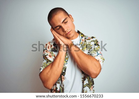 Young handsome man on holidays wearing Hawaiian shirt over white background sleeping tired dreaming and posing with hands together while smiling with closed eyes.