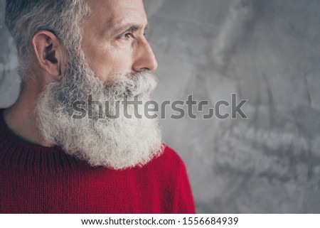 Cropped closeup photo of serious aged guy looking side empty space minded wear red knitted pullover cool hipster santa outfit isolated concrete grey wall background