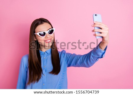 Photo of trendy beautiful attractive charming woman on vacation taking selfie abroad smiling toothily enjoying summer time wearing blue shirt sunglass isolated pink pastel color background