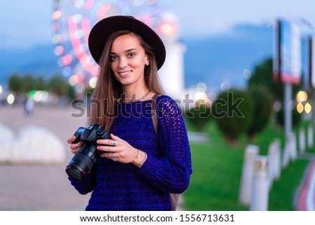 Portrait of happy beautiful casual stylish hipster traveler woman photographer in hat with a digital dslr camera during taking photos outdoors 