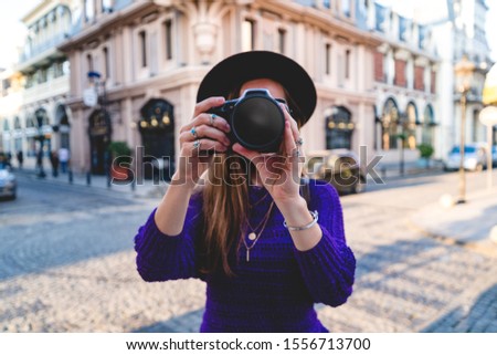 Woman photographer taking pictures using dslr camera during walking around european city
