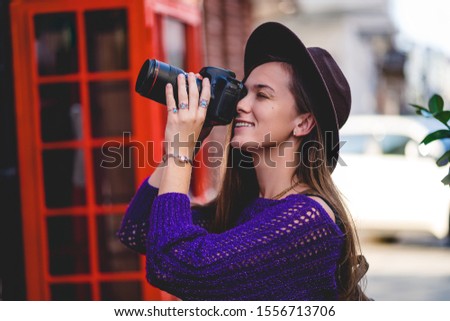 Happy cute attractive casual young traveler hipster woman photographer in hat with dslr digital photo camera during taking photos in the city in travel time 