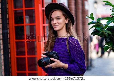 Happy cute attractive casual young traveler hipster woman photographer in hat with camera during walking around the city
