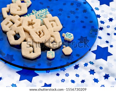 Chanukah dreidel cookies on a blue glass plate  with copy space